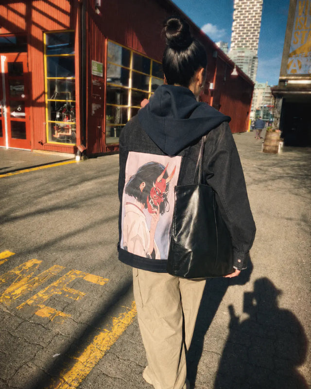 Person walking in a black jacket with a pink demon-mask art panel.