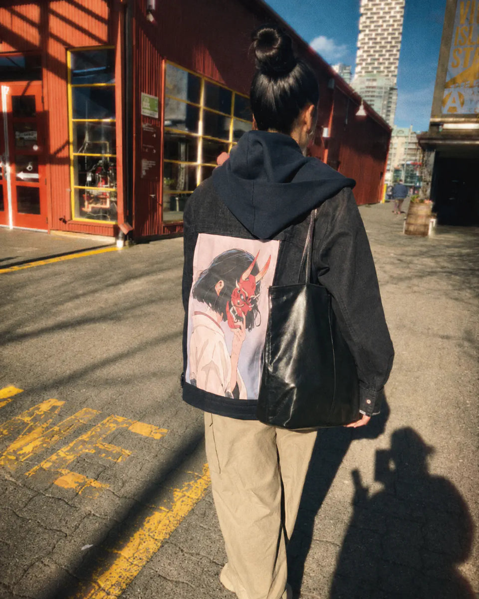Person walking in a black jacket with a pink demon-mask art panel.