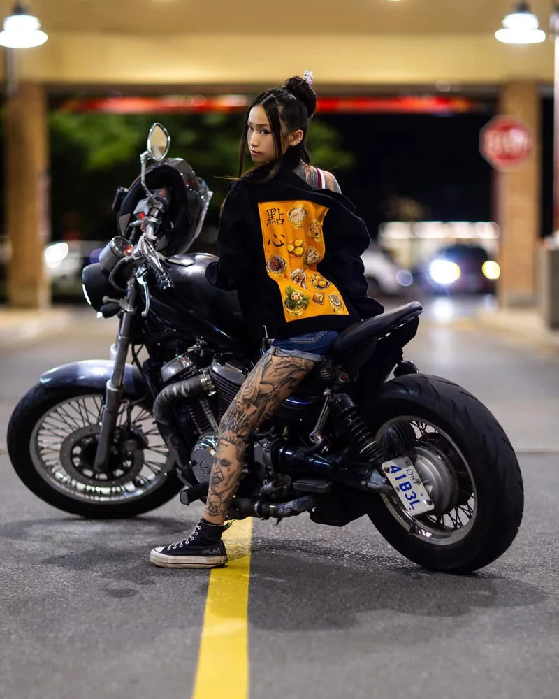 Creator wearing an Onyx hoodie with Dim Sum art while seated on a motorcycle at night.