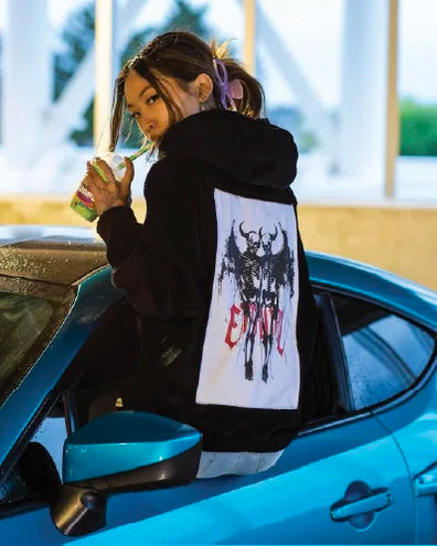 Creator wearing an Onyx hoodie with Eternal Love art beside a turquoise sports car.