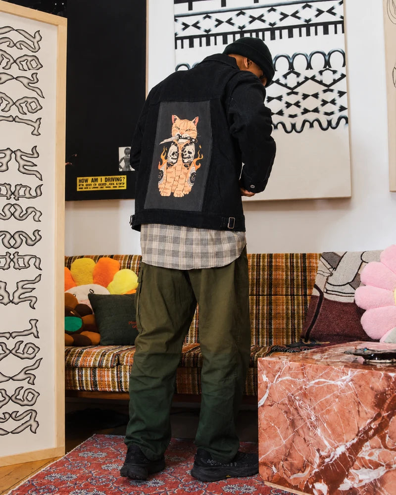 Customer looking down in a Raven denim jacket with Catana Skull artwork in an art gallery.