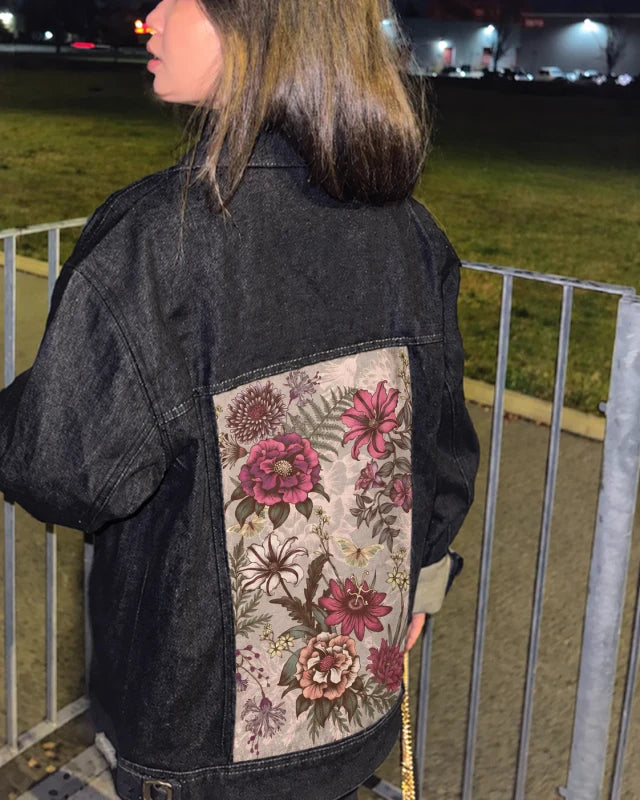 A black Raven Denim Jacket styled with Garden Florals art beside a railing at night.