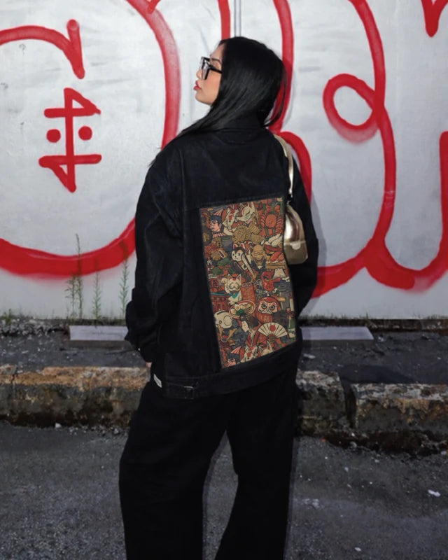 A black OG Denim Jacket styled with Yamato art beside a graffiti wall.