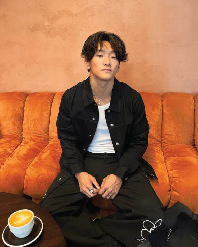 Customer wearing a black OG Denim Jacket with a white tee while seated in a cafe.
